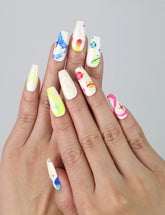 Hand showcasing coffin-shaped medium press on nails with neon squiggles, star accents, and vibrant abstract designs by Naillover